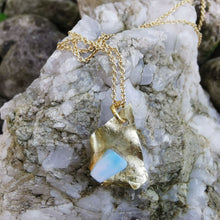 Load image into Gallery viewer, Opal and  brass pendant photographed on rock