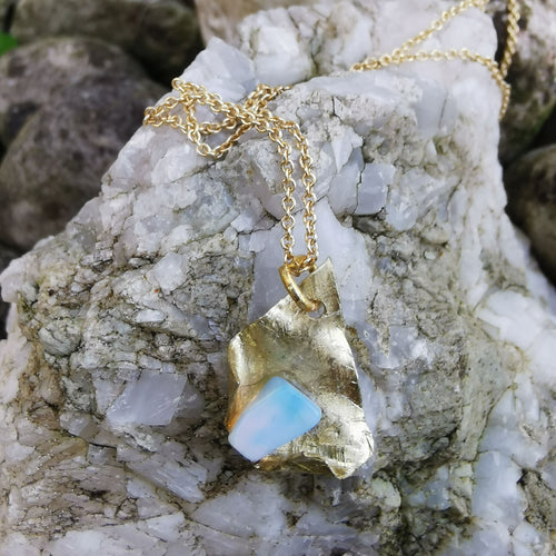 Opal and  brass pendant photographed on rock