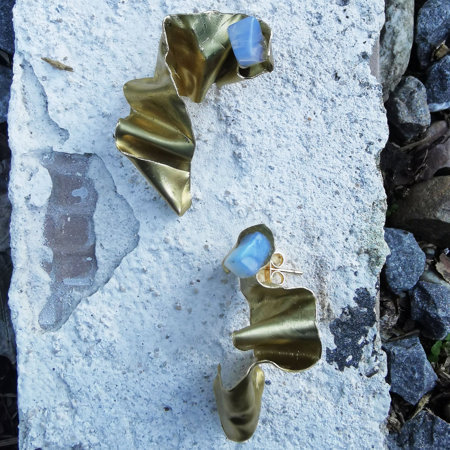 Wrapped up brass opal and gold plated earring on marble