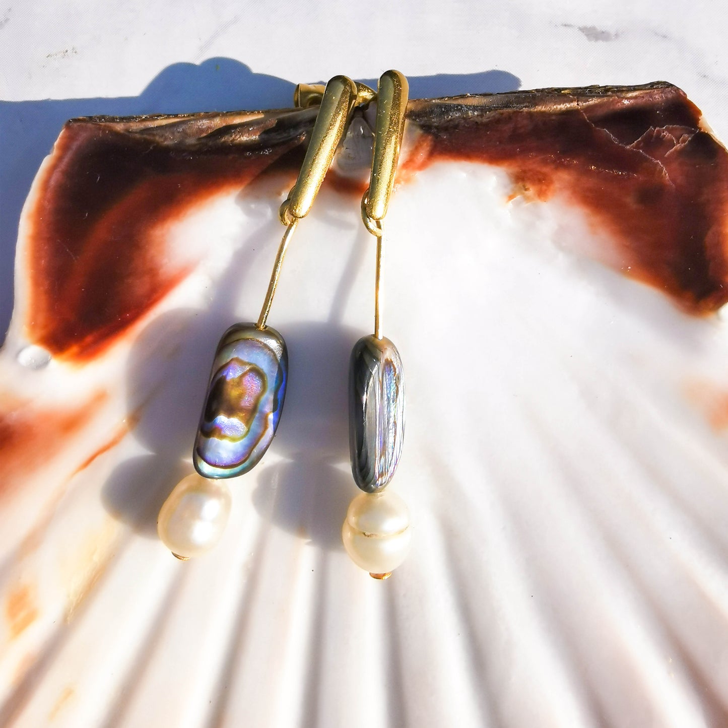 Paua shell, freshwater pearl bar earrings leaned on shell
