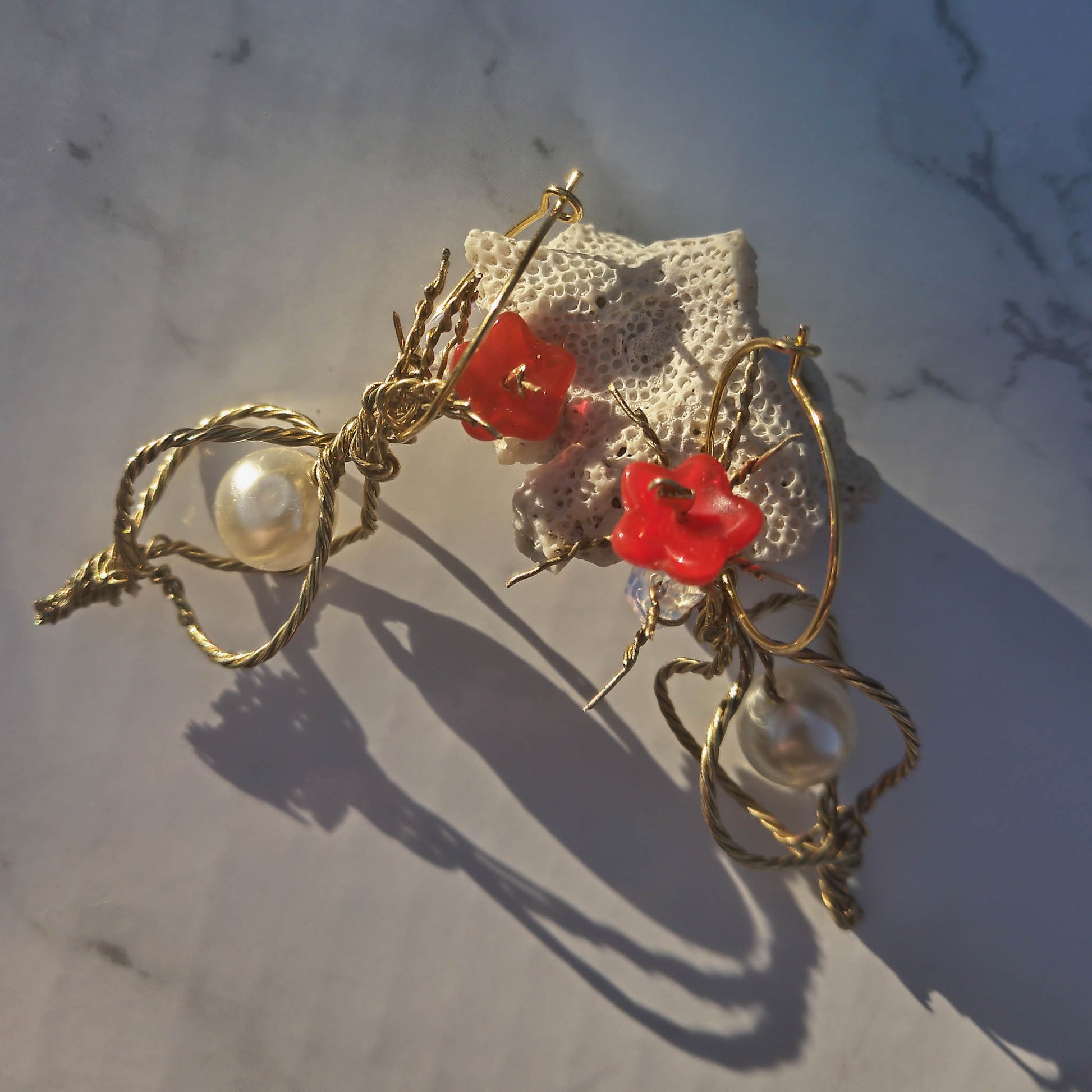 Twisted wire earrings with pearl, red flower bead and opal earring details.