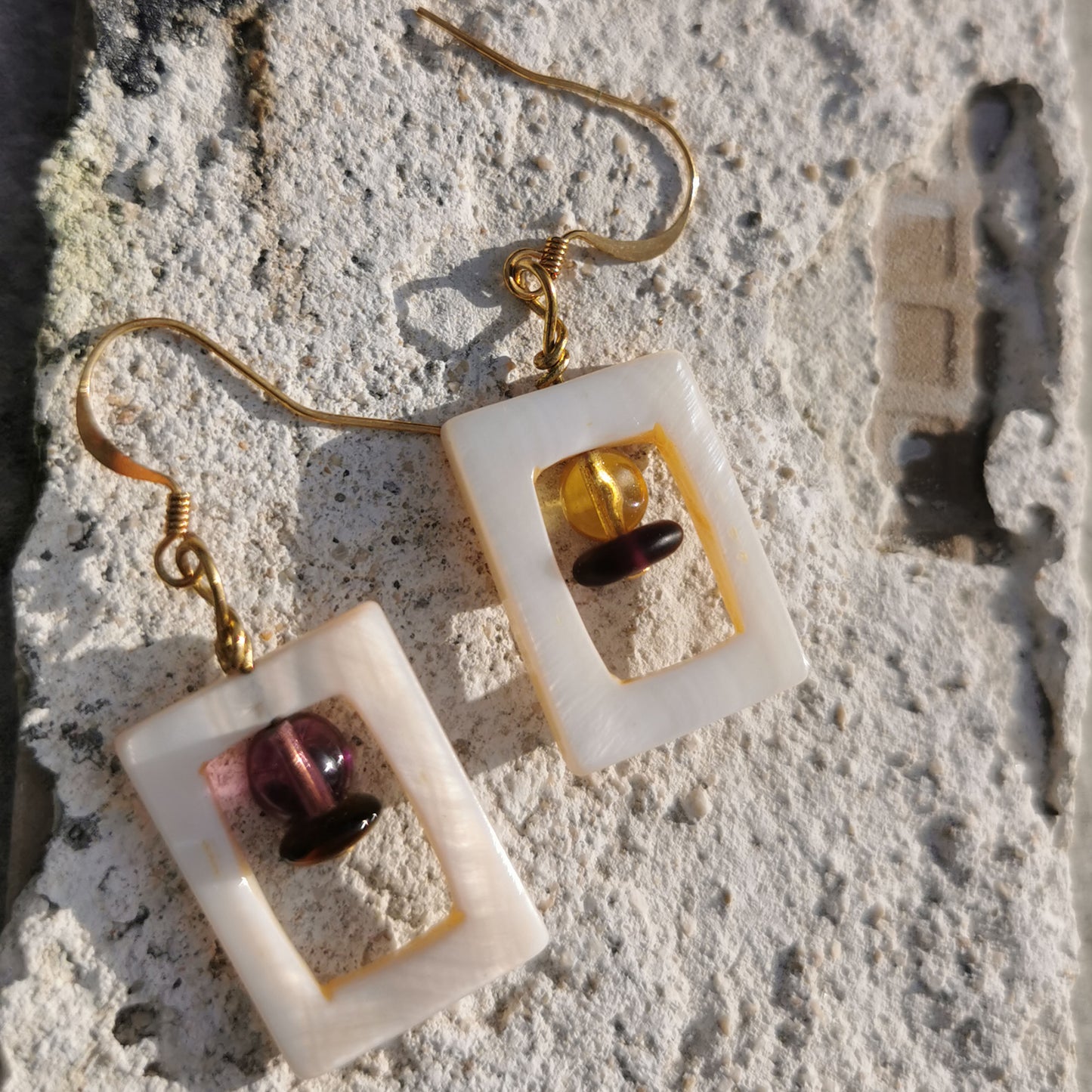 Earrings with purple and yellow beads enclosed within a shell