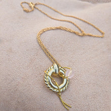 Load image into Gallery viewer, Necklace with textured holed pendandt with an intertwined chain holding a pink bead 
