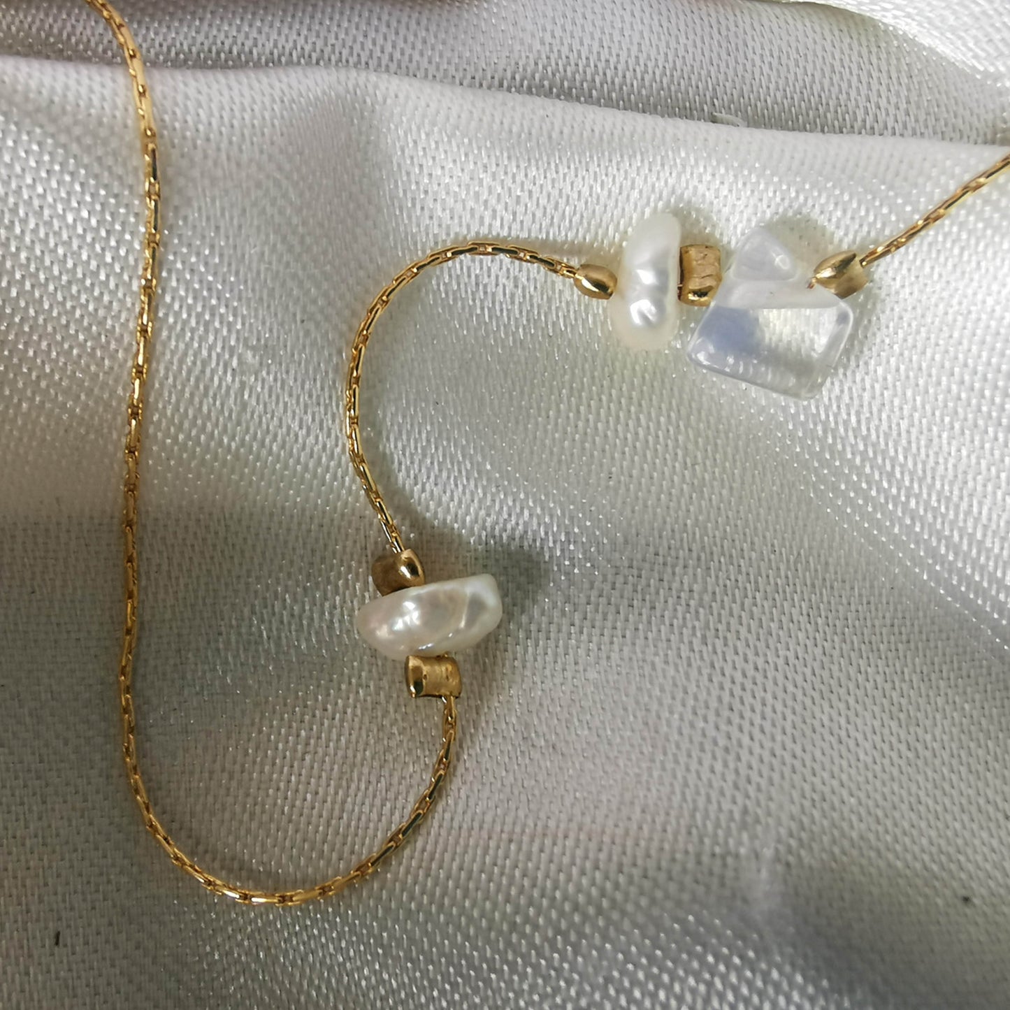 Close up fo pearls and opal necklace on gold olates snake chain