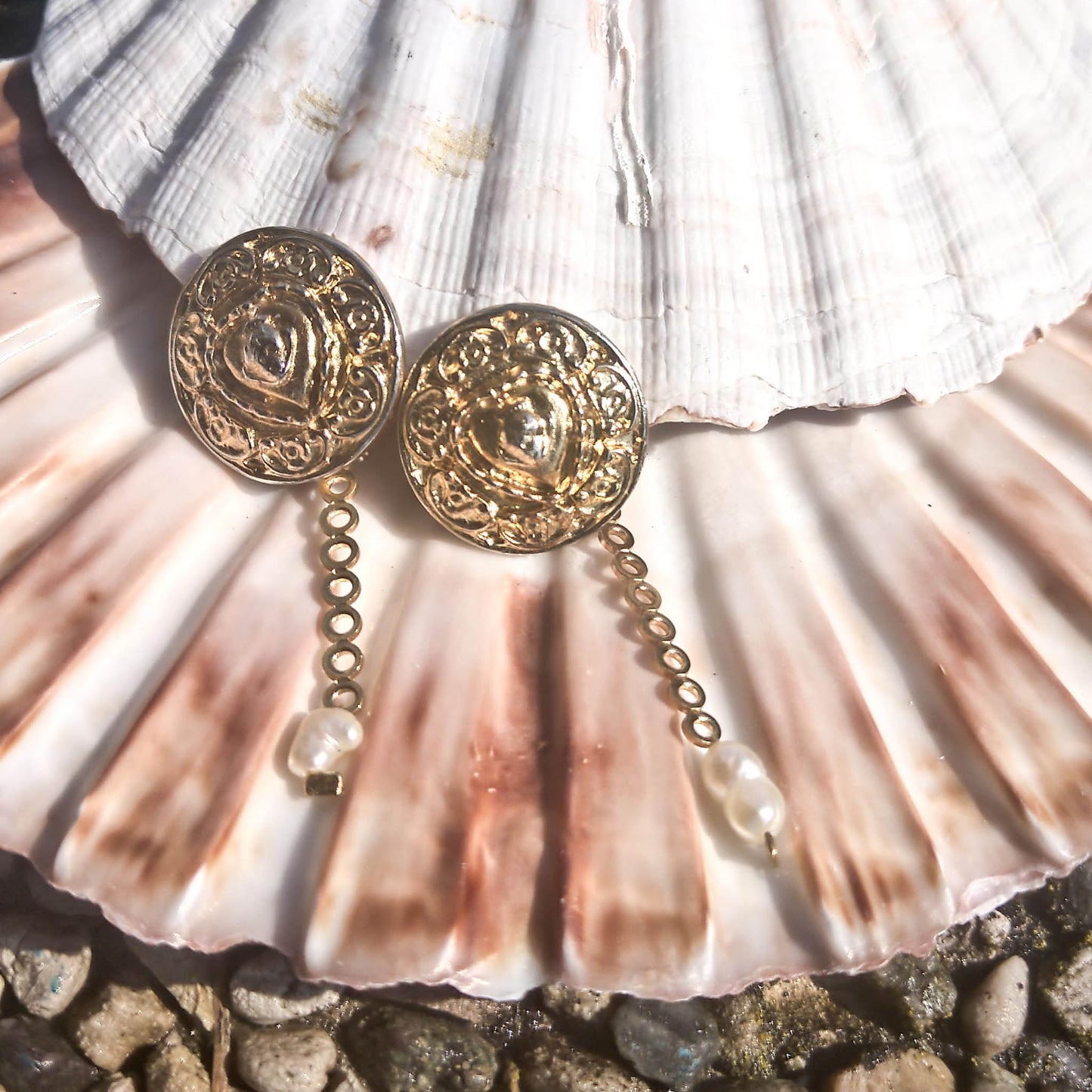 Donatella earrings- textured stud earrings with dainty freshwater pearl detail lying on a shell  