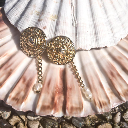 Donatella earrings- textured stud earrings with dainty freshwater pearl detail lying on a shell  
