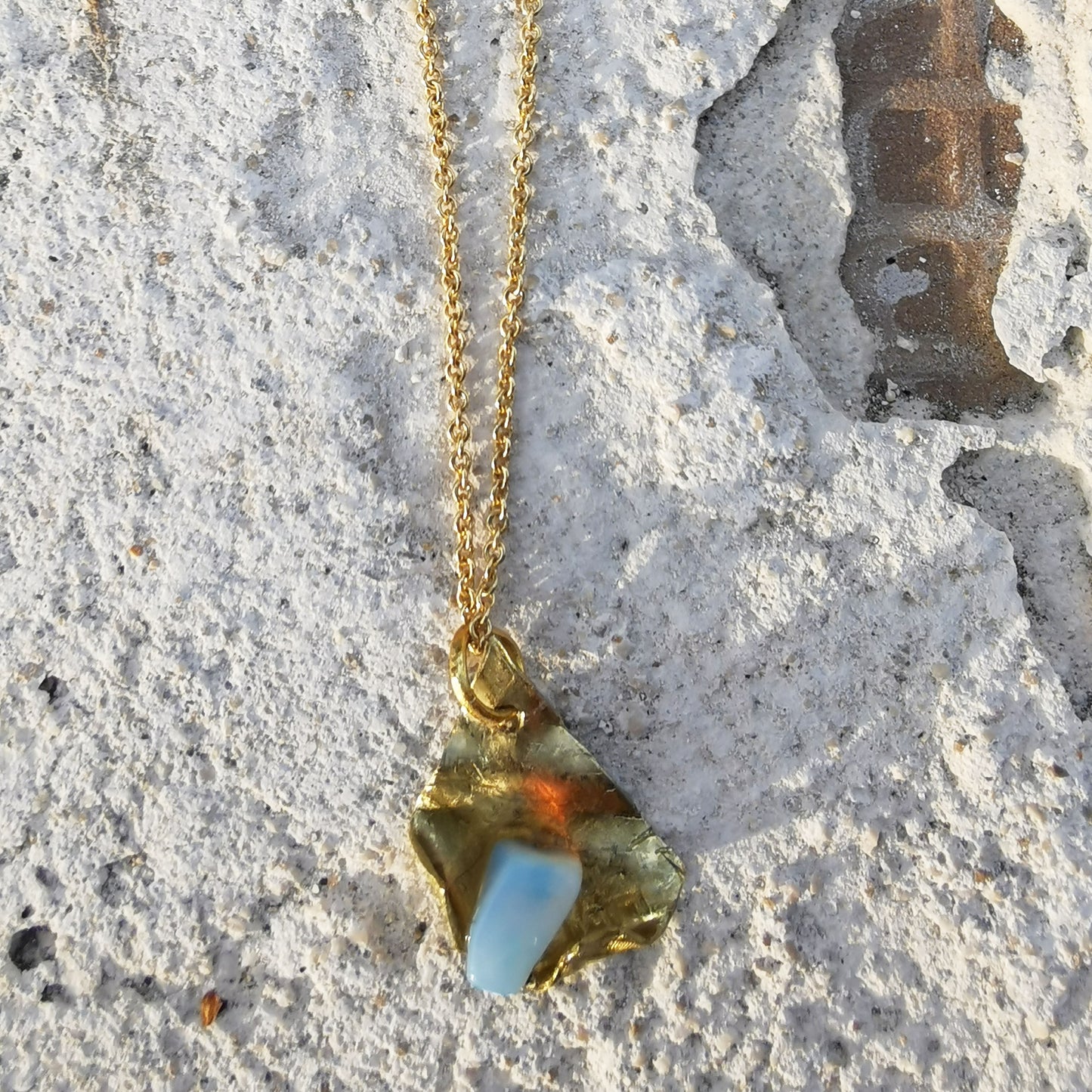 Opal and brass pendant on white brick texture 