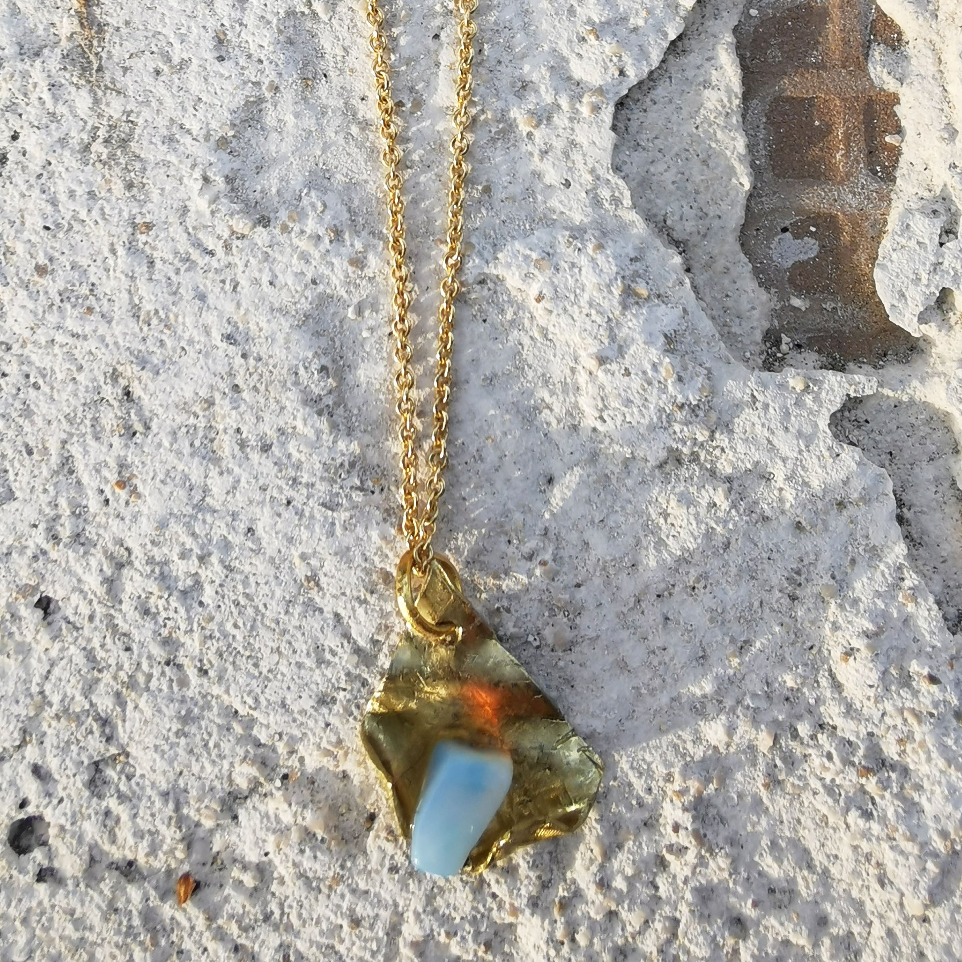 Opal and brass pendant on white brick texture 