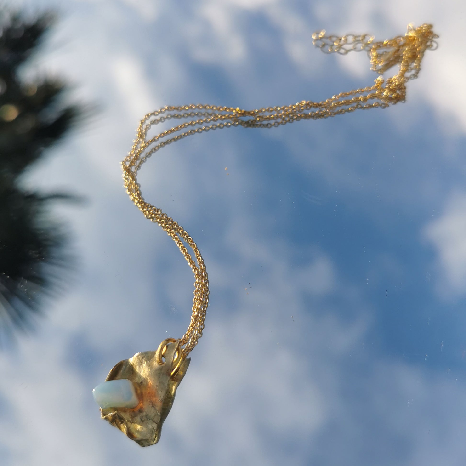 Opal and brass necklace photographed in mirror reflection