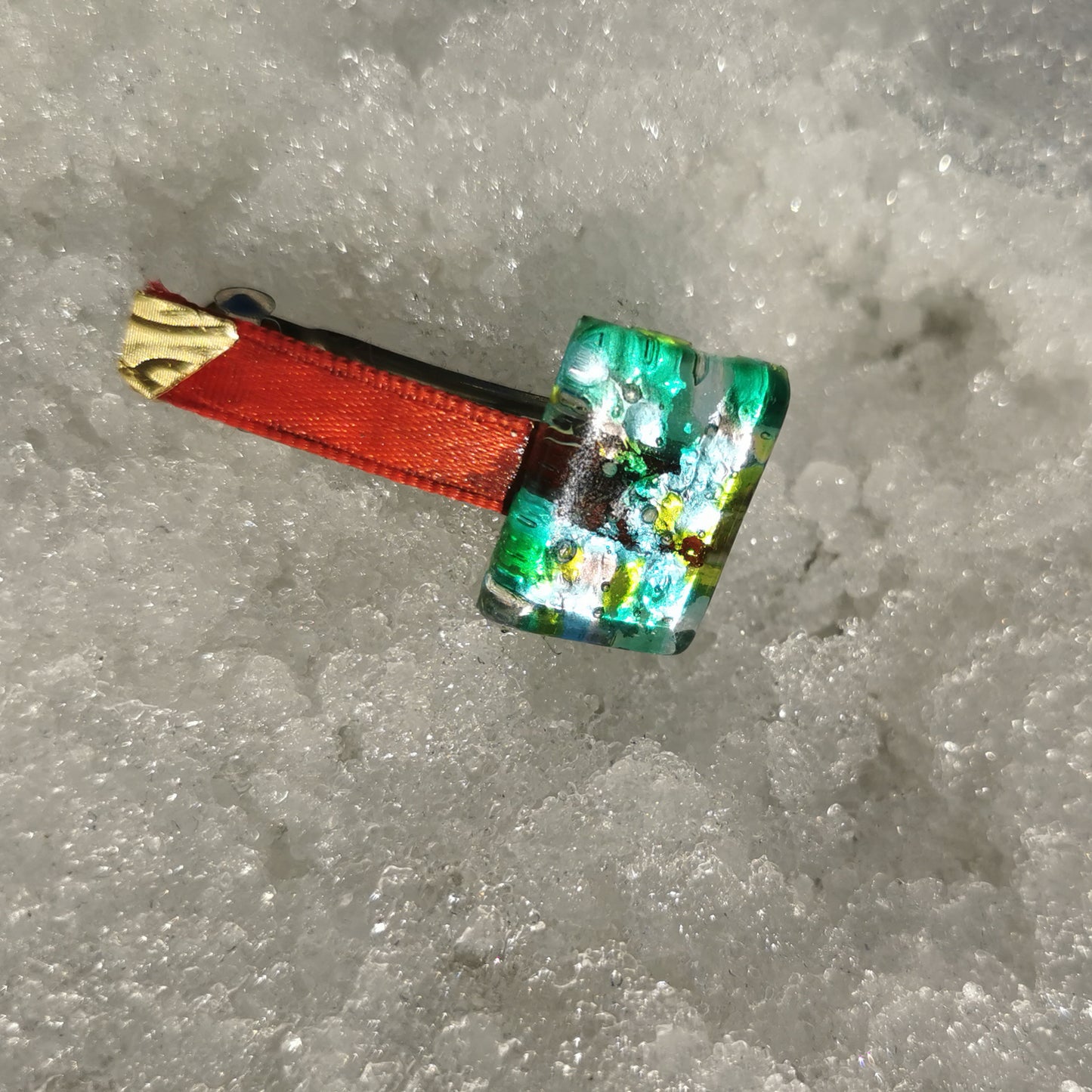 Green glass, brass red ribbon in snow