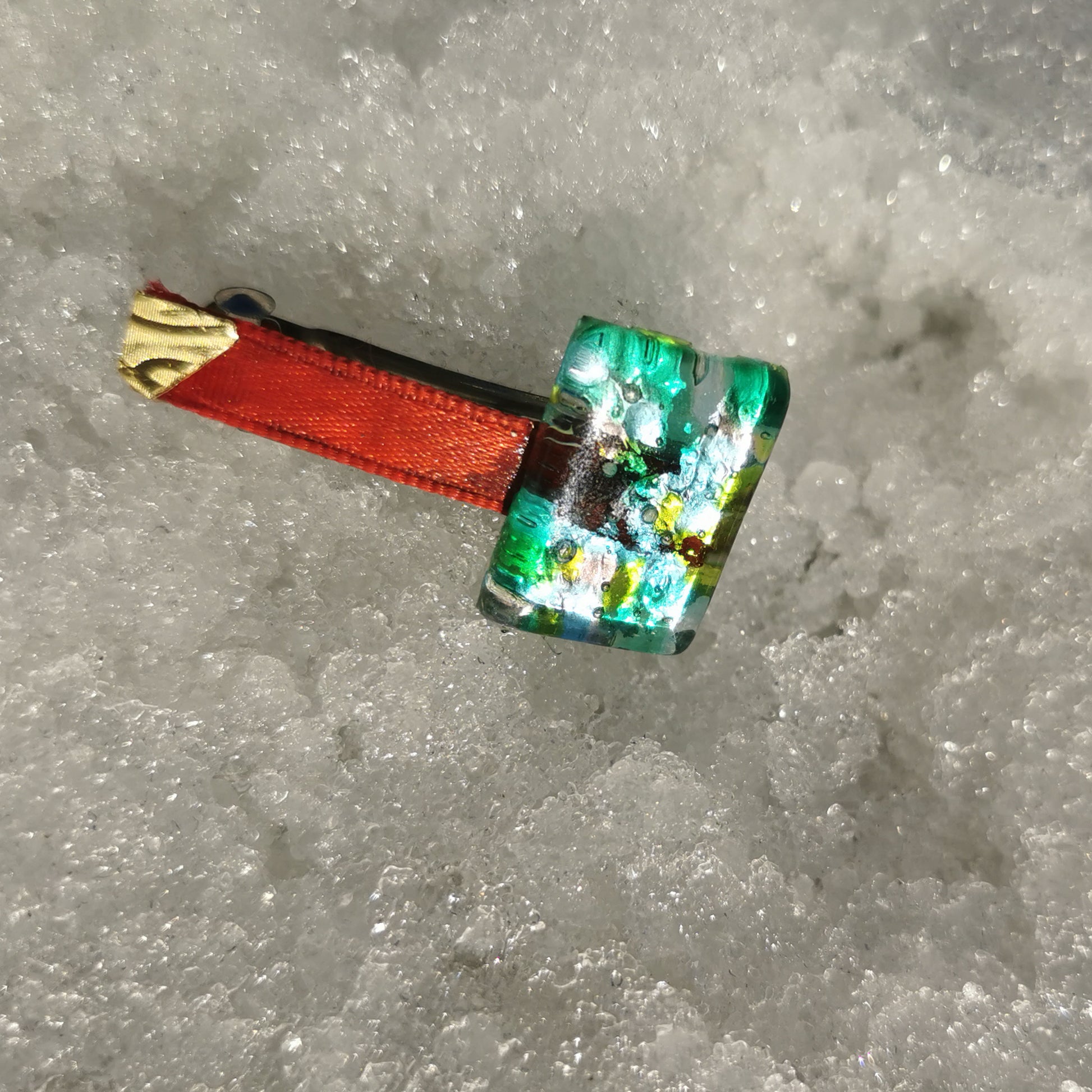 Green glass, brass red ribbon in snow