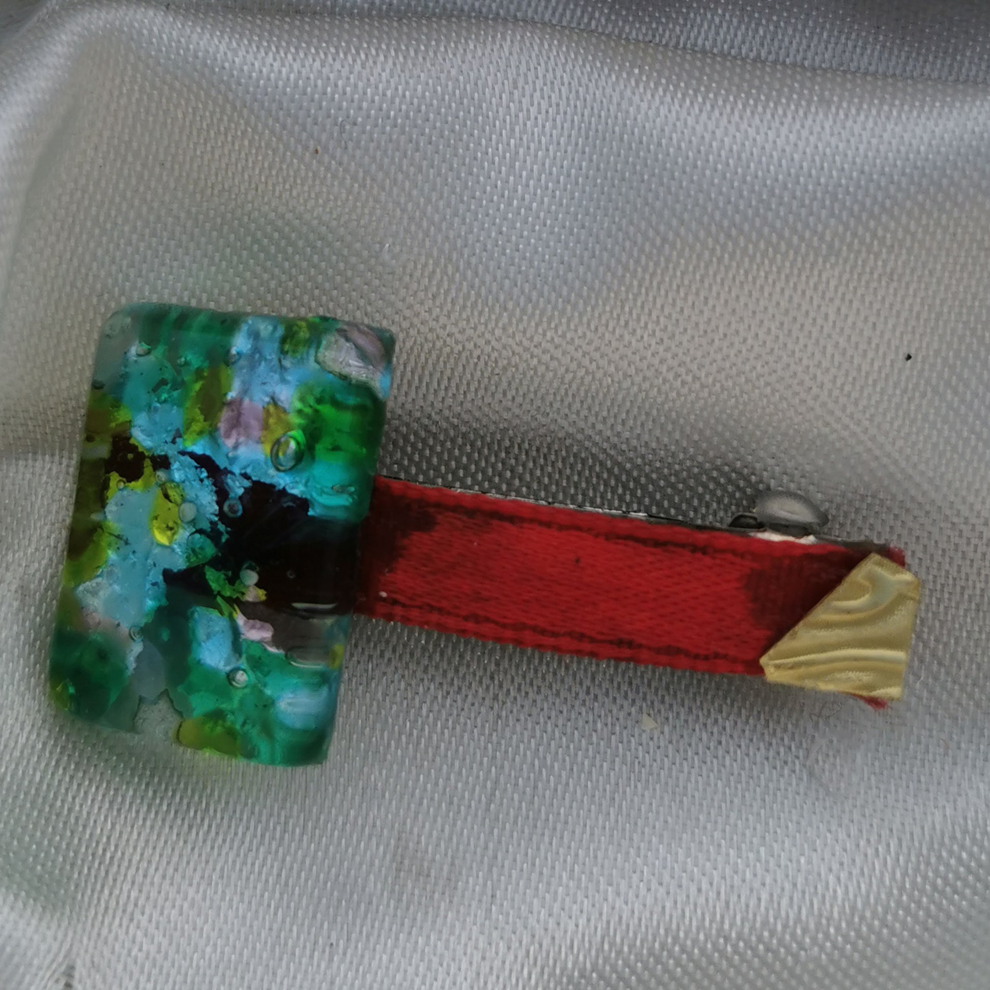 Green glass, red ribbon and brass