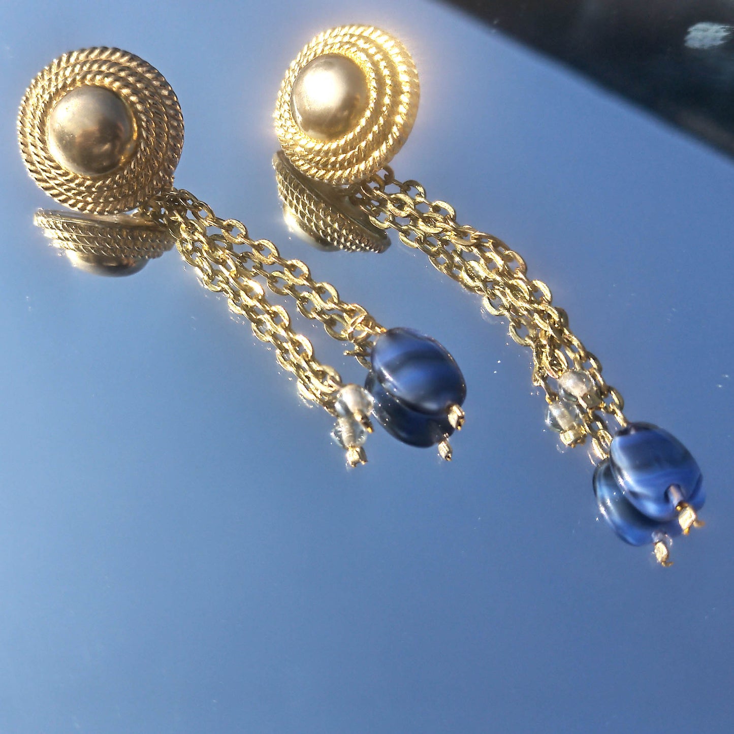 Textured stud with cable chain dangle and blue and see-through beads reflected in mirror