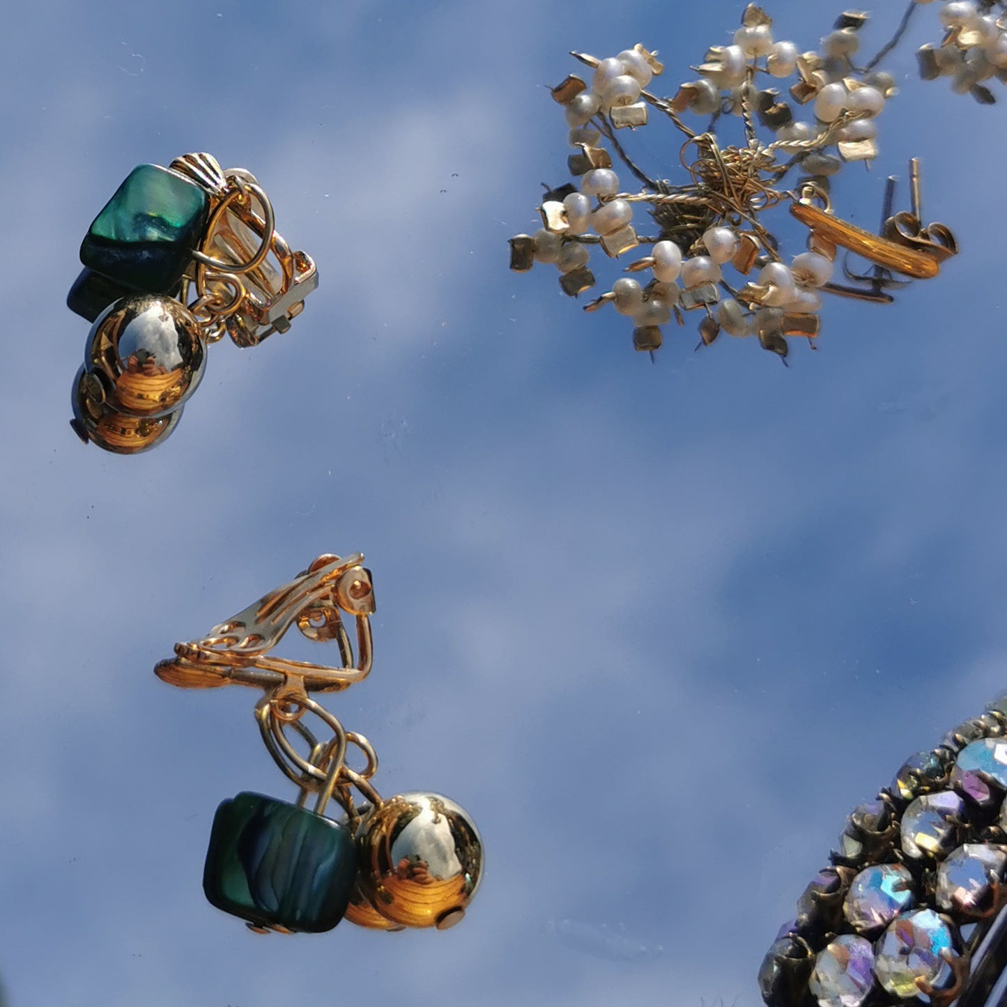 Green and gold bell plated earrings on mirror background