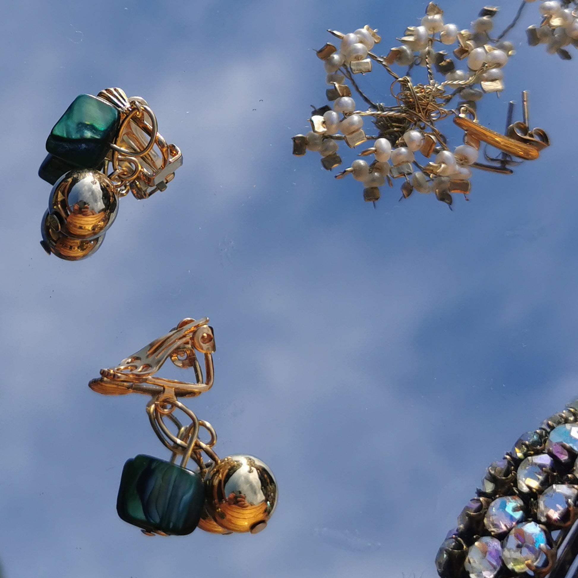 Green and gold bell plated earrings on mirror background