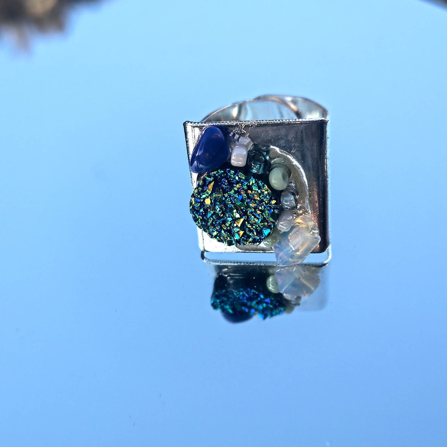 Silver coloured ring with blue, mint and opal details  close up 