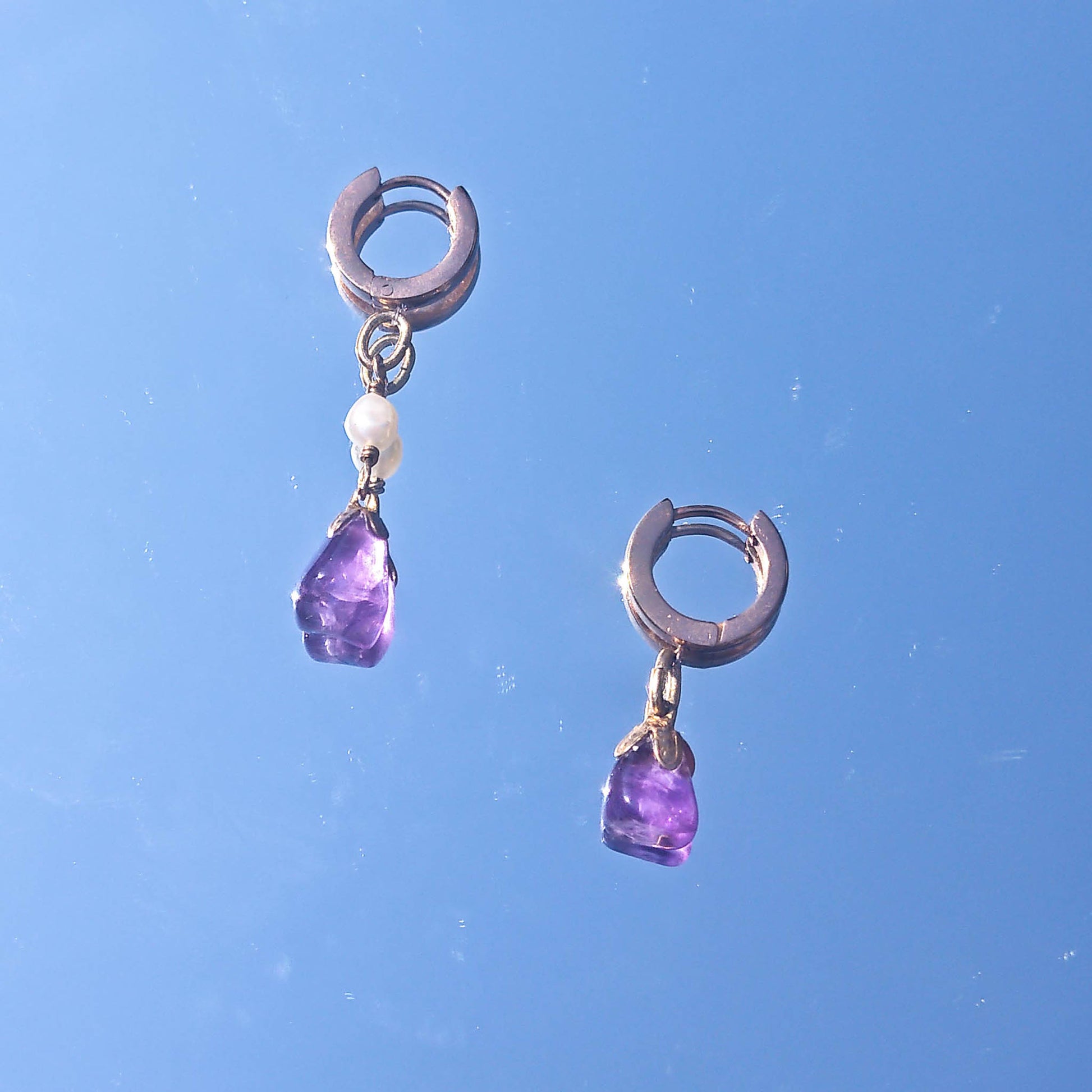 Mixmatch and asymmetric amethyst freshwater pearl earrings reflected in mirror
