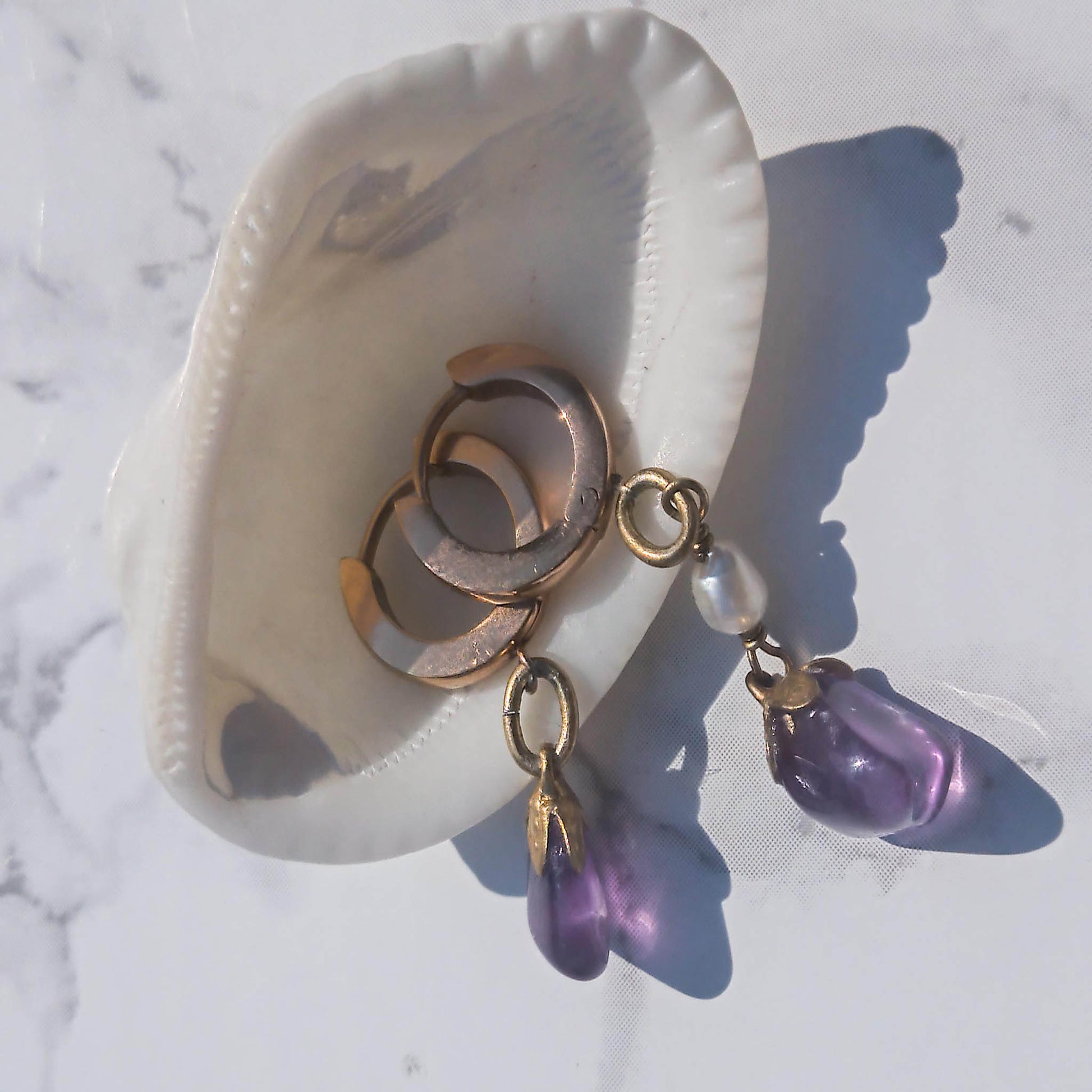 Mixmatch and asymmetric amethyst freshwater pearl earrings photographed with shell