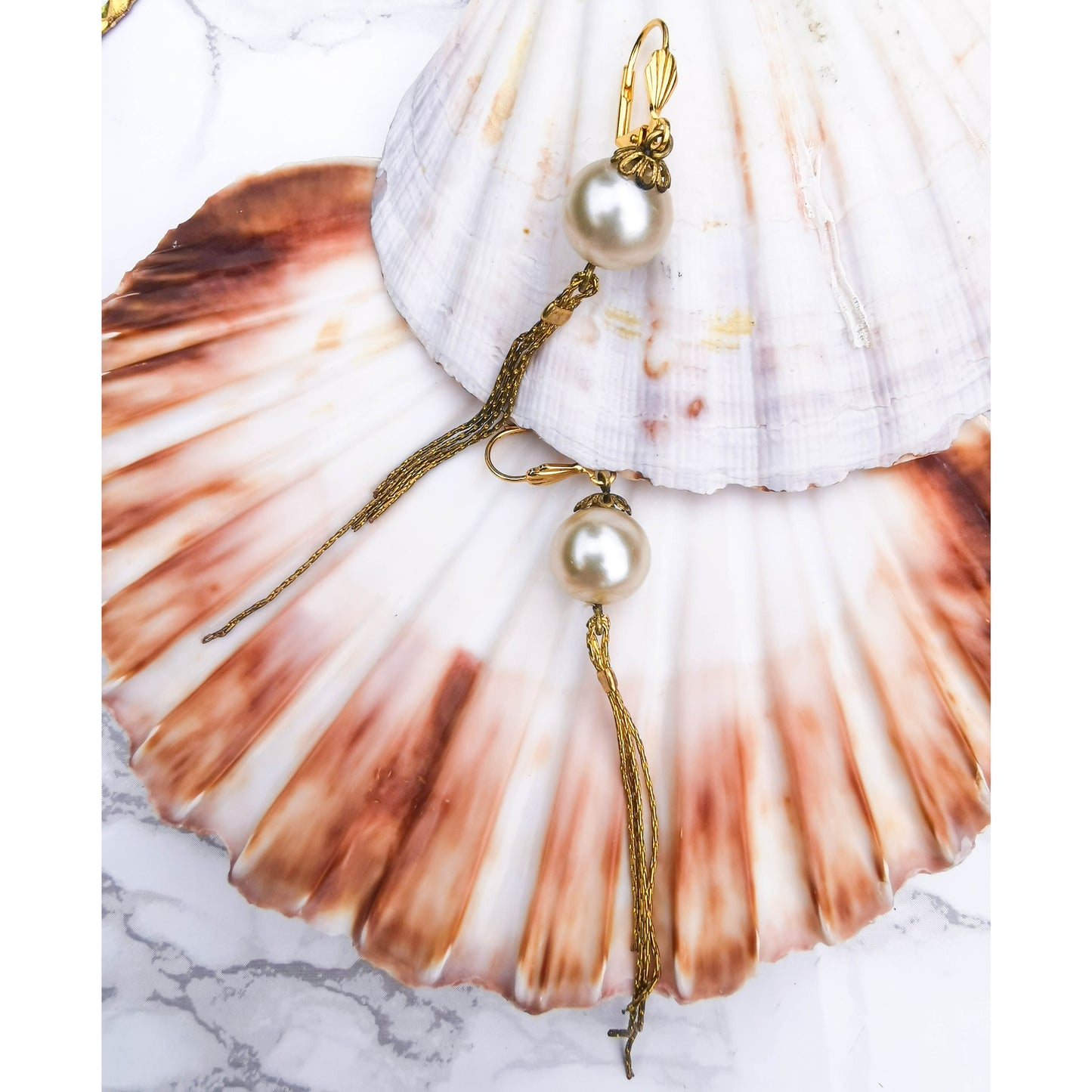 Pearl earrings with tassle and fan detail photographed on shells 