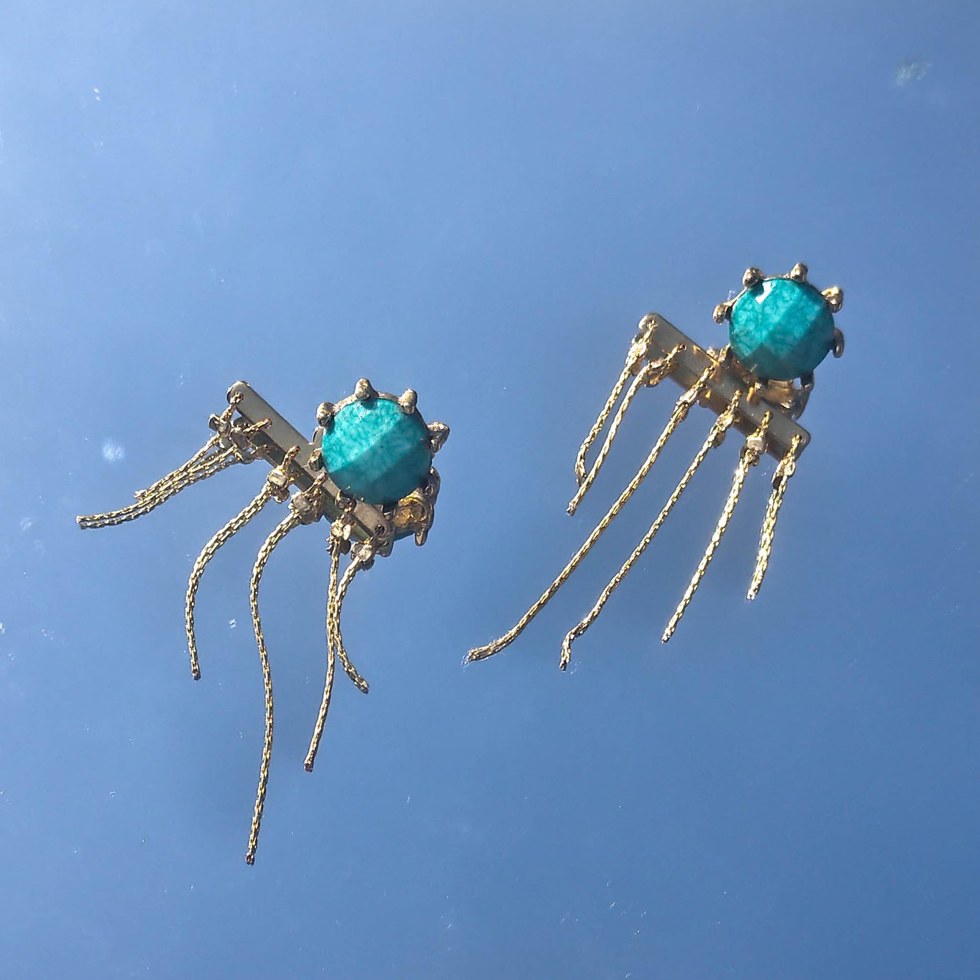 turquoise studded earrings with reflection on them