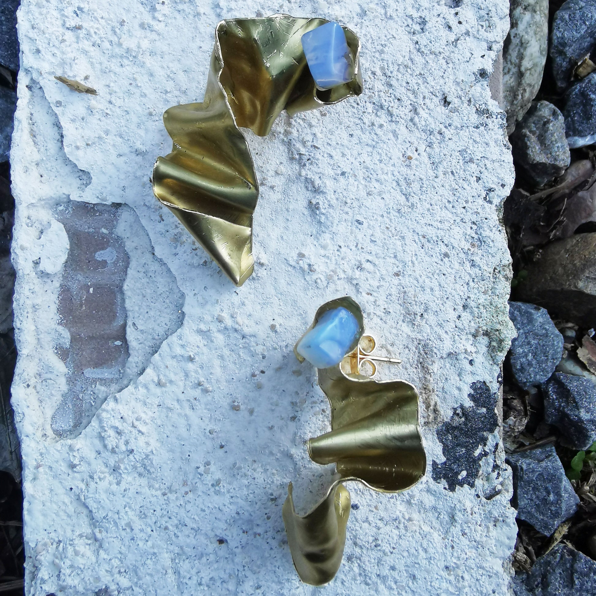 Wrapped up brass opal and gold plated  earring on marble 